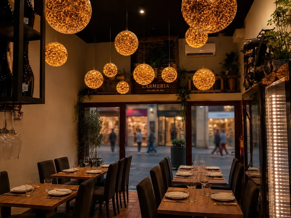 Interior del restaurante mediterráneo L'Armeria en Molins de Rei con lámparas esféricas doradas sobre el Carrer Major